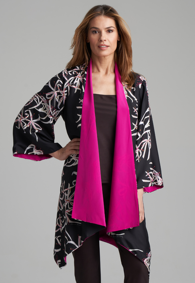 Woman wearing silk black spider lily printed reversible pink robe jacket over black stretch knit tank top and pant by Ala von Auersperg