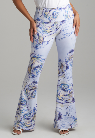 Woman wearing blue rose printed stretch knit flare pants and white stretch knit tank top by Ala von Auersperg for spring summer 2022