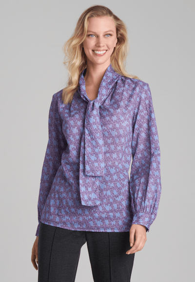 Woman wearing purple and blue bird printed cotton blouse and stretch knit plaid pants by Ala von Auersperg for fall 2022
