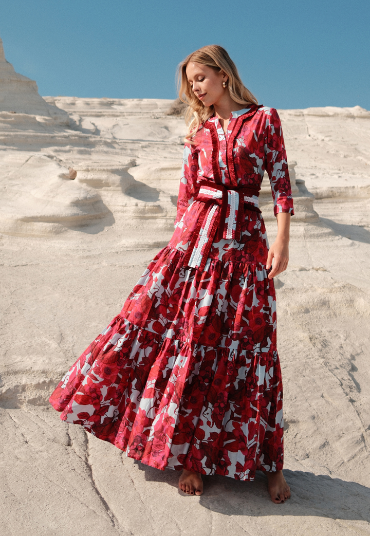 Woman in a red dress with white patterns standing on a stone staircase.