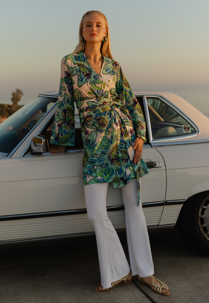 Woman in a floral kimono and white pants standing next to a vintage car