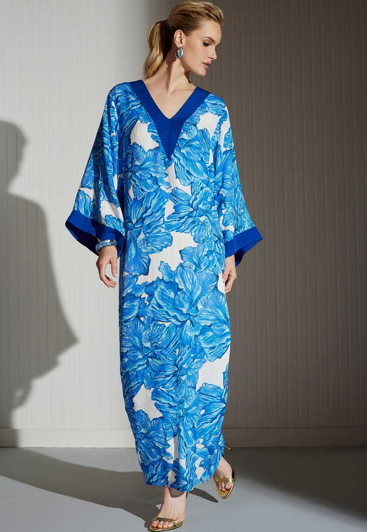 Woman wearing silk blue floral printed kaftan with blue trim by designer Ala von Auersperg for women's luxury fashion