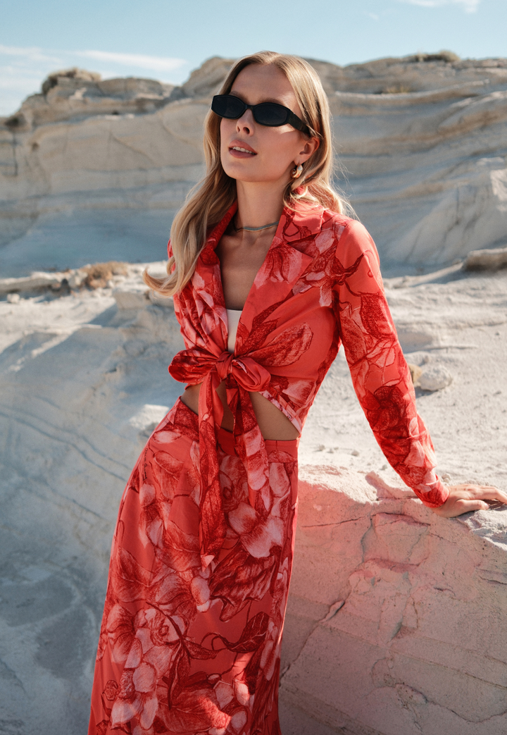 Woman in a red floral dress standing in a desert landscape