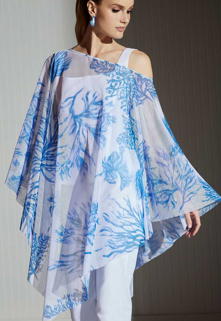 Woman wearing sheer mesh poncho in blue and white print over Italian cotton tank top and pants in white by designer Ala von Auersperg for luxury women's clothing