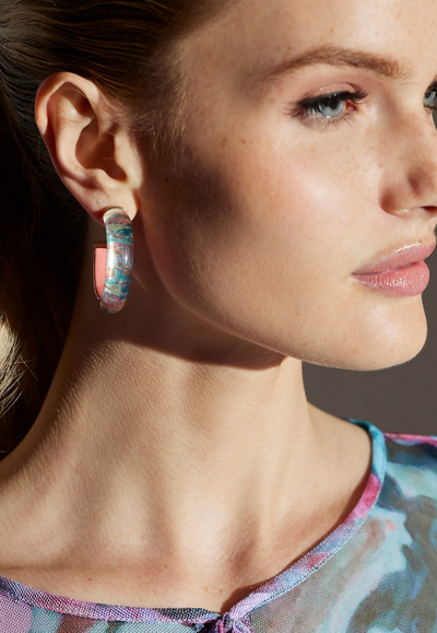 Woman wearing small pink floral lucite hoop earrings with coral detail and 14K gold plated hardware