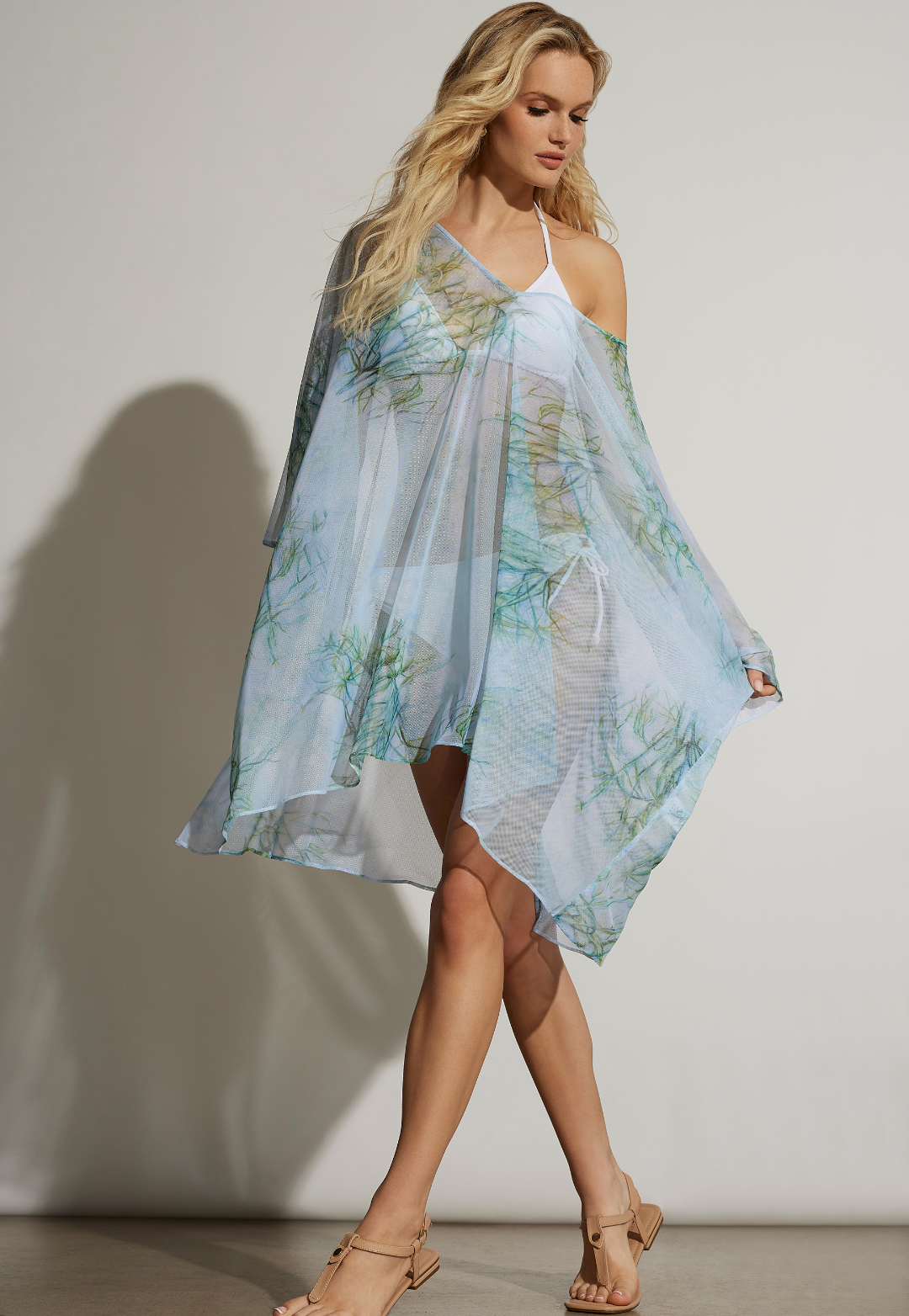 Woman wearing light blue and green printed mesh kaftan over a white bikini