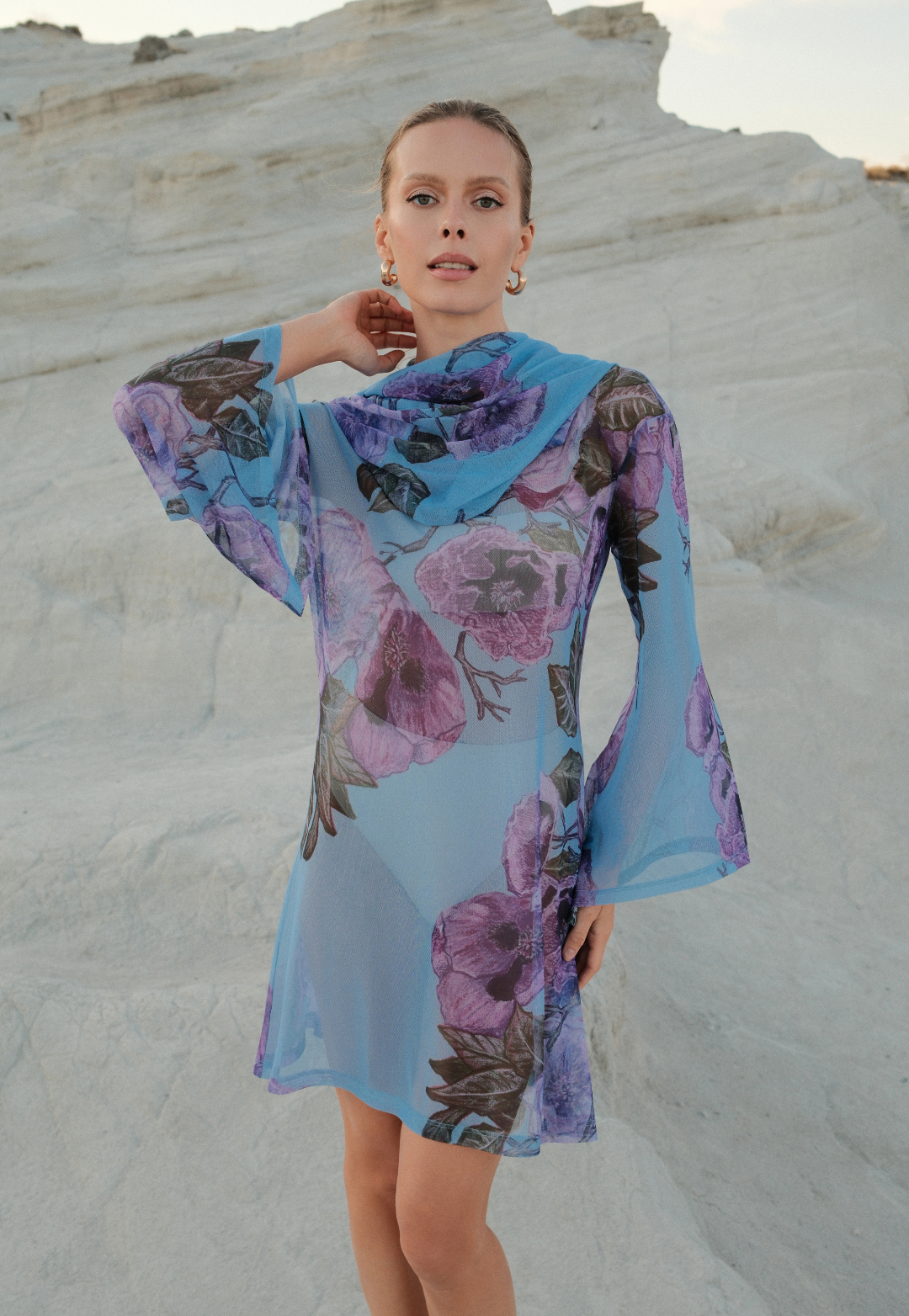 Woman wearing a floral dress with bell sleeves against a white sand dune background