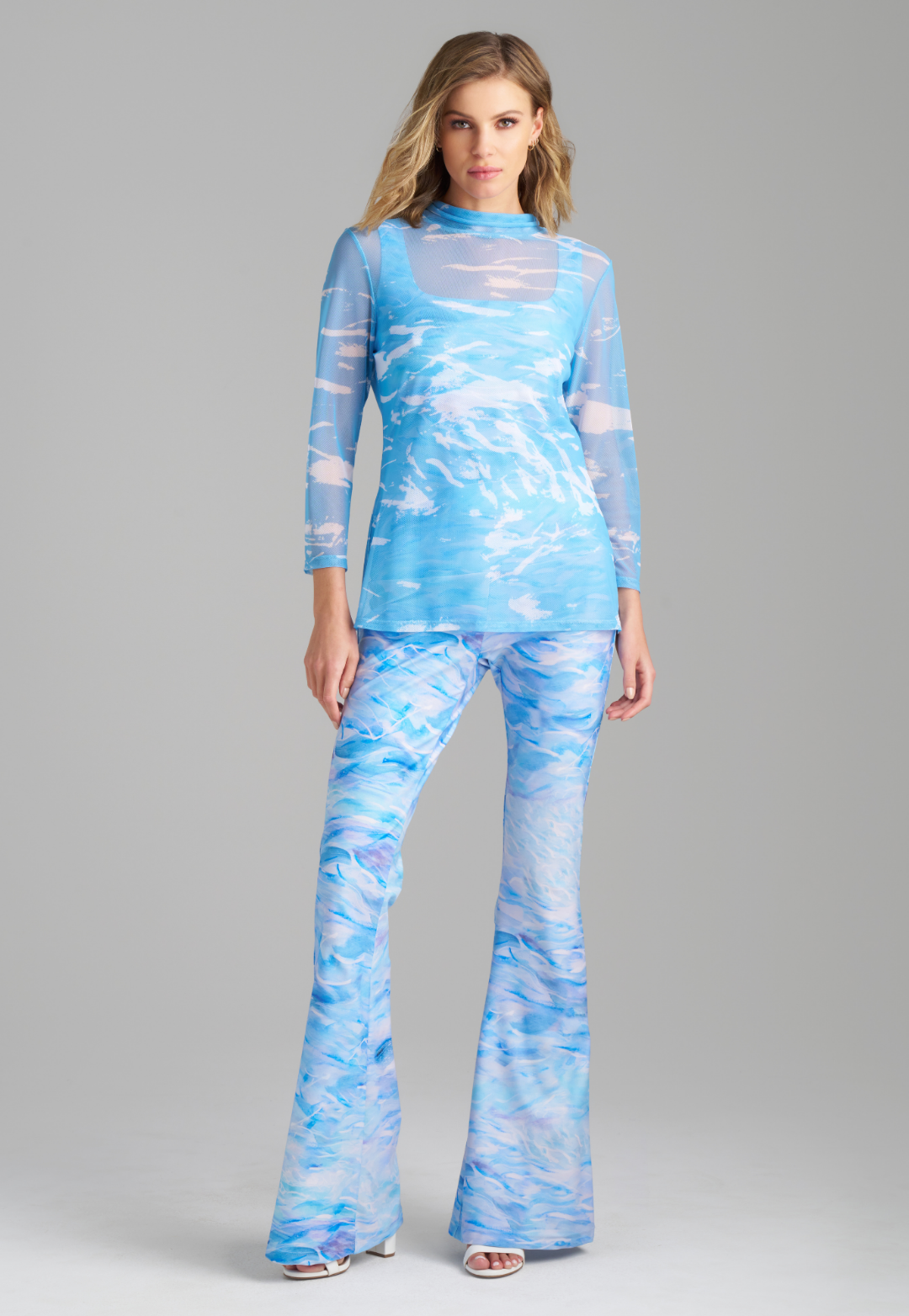 Woman wearing blue wave printed mesh turtleneck over wave printed stretch knit tank top and pant by Ala von Auersperg for summer 2023