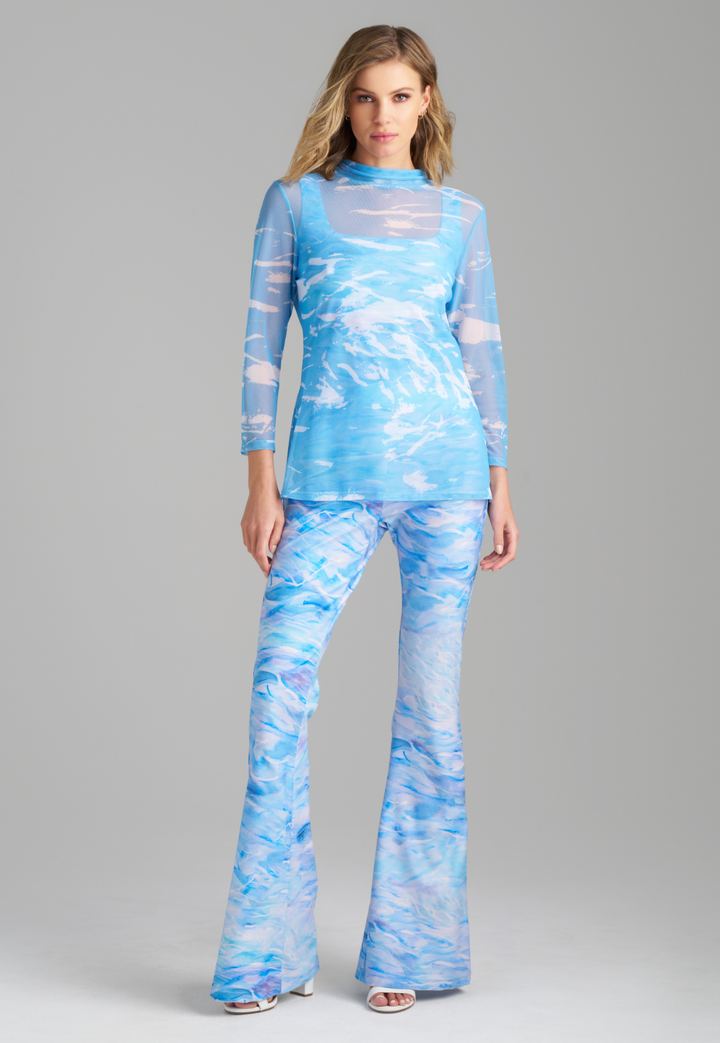 Woman wearing blue wave printed mesh turtleneck over wave printed stretch knit tank top and pant by Ala von Auersperg for summer 2023