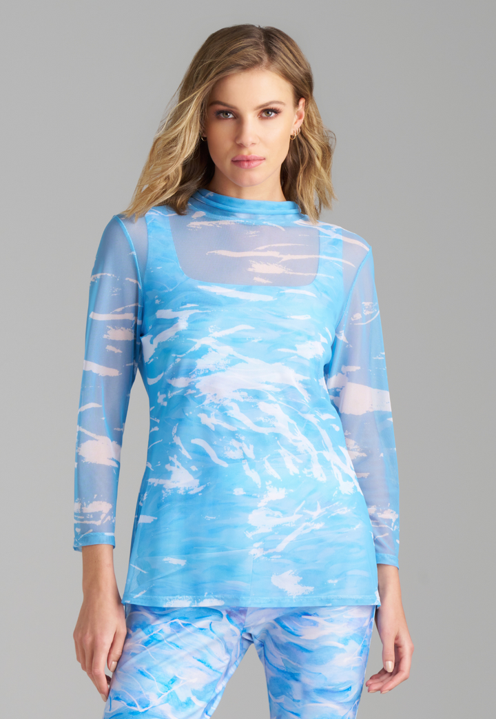 Woman wearing wave printed blue mesh turtleneck over stretch knit tank top and pants by Ala von Auersperg for summer 2023