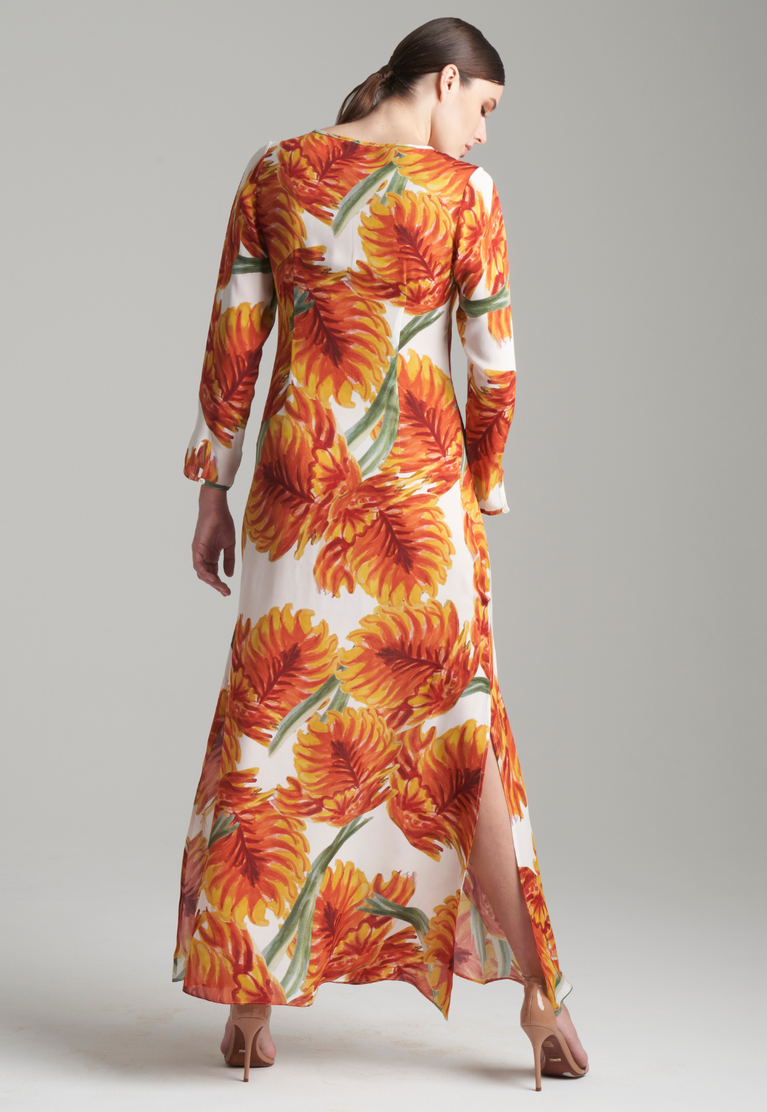 Woman wearing silk keyhole kaftan and dress in orange and white palm leaf print