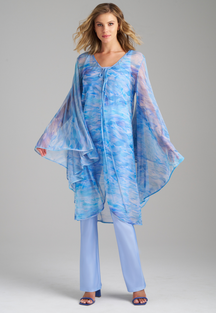 Woman wearing ocean wave printed mesh blue duster with angel sleeves over periwinkle stretch knit tank top and pants by Ala von Auersperg for summer 2023