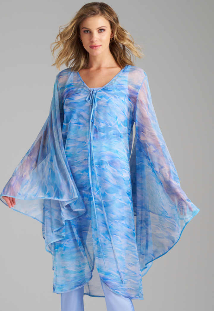 Woman wearing ocean wave printed mesh blue duster with angel sleeves over periwinkle stretch knit tank top and pants by Ala von Auersperg for summer 2023