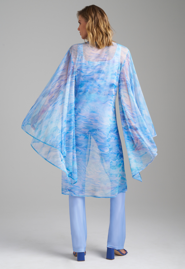 Woman wearing ocean wave printed mesh blue duster with angel sleeves over periwinkle stretch knit tank top and pants by Ala von Auersperg for summer 2023