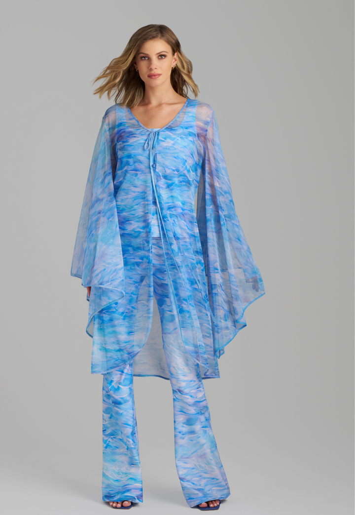 Woman wearing ocean wave printed mesh blue duster with angel sleeves over periwinkle stretch knit tank top and pants by Ala von Auersperg for summer 2023