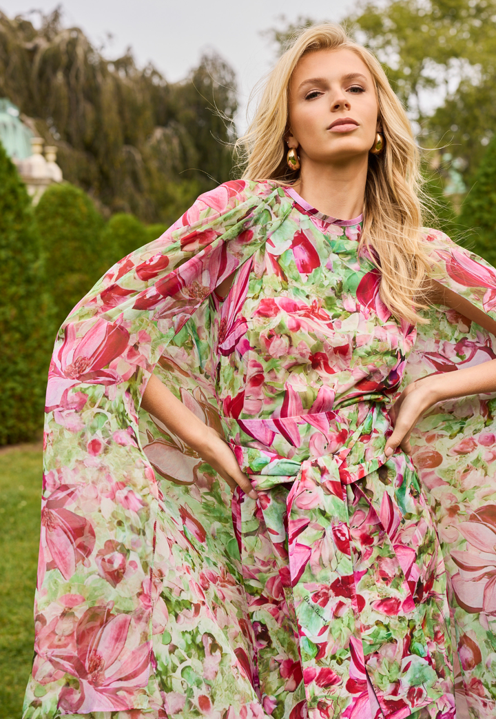 Woman wearing a pink and green floral dress in an outdoor setting