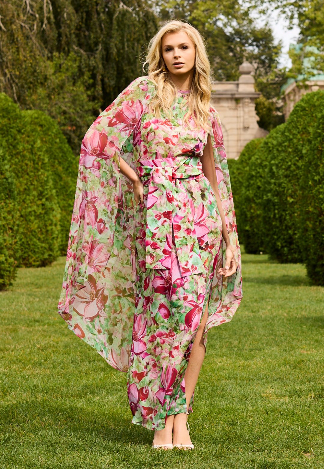 Woman wearing a floral dress and cape in a garden setting
