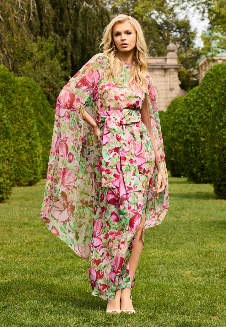 Woman wearing a floral dress and cape in a garden setting