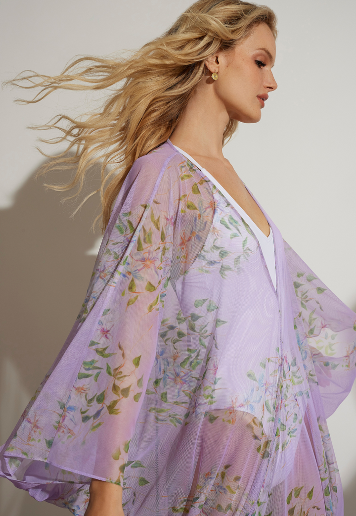 Woman wearing purple floral mesh cover up over a white bathing suit 