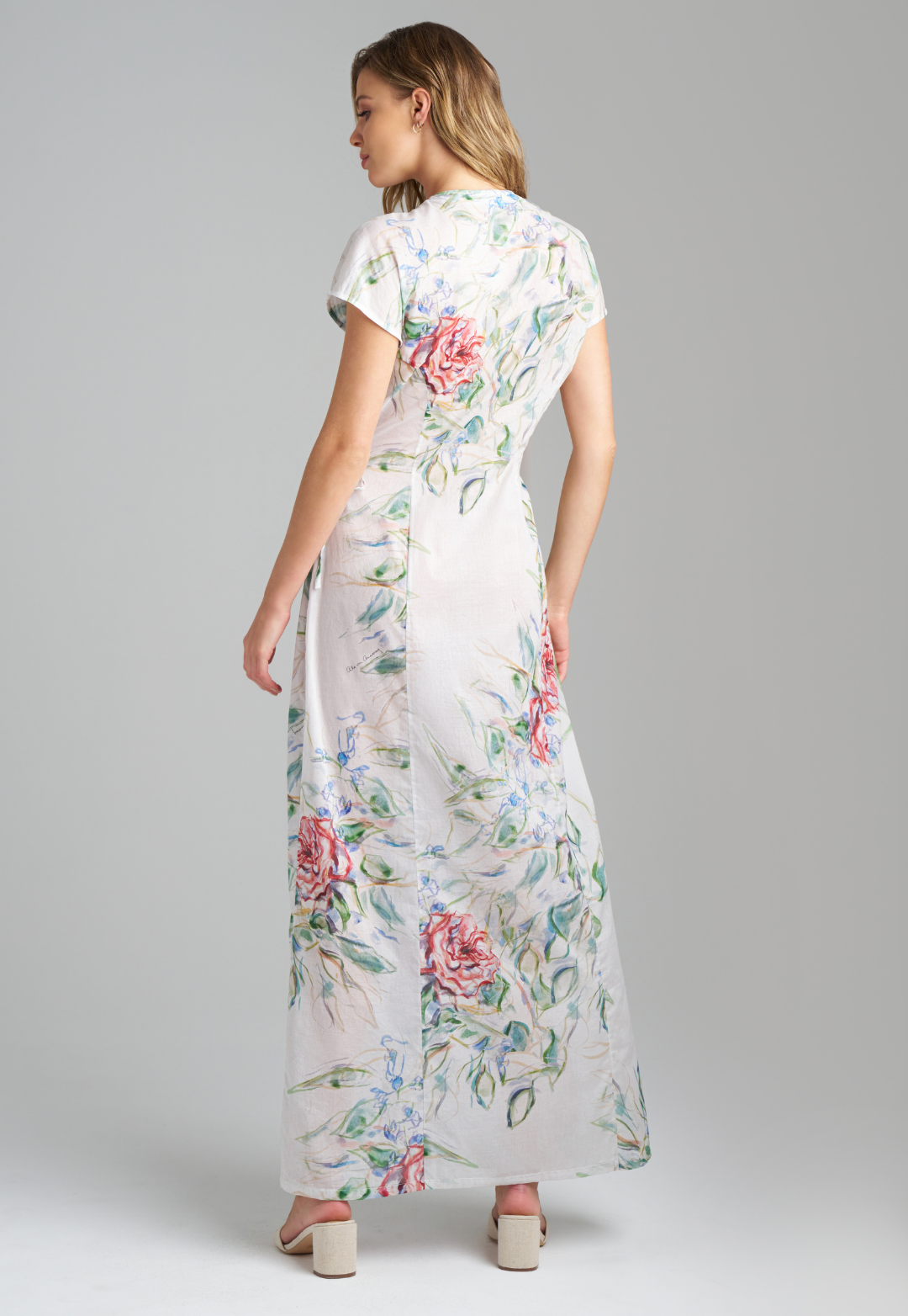 Woman wearing rose printed cotton wrap dress with v neck, side tie, and short sleeves by Ala von Auersperg for summer 2023