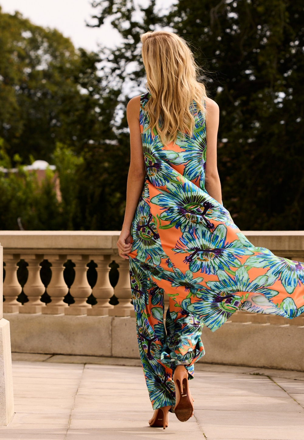 Woman wearing a colorful top and pants walking outdoors.