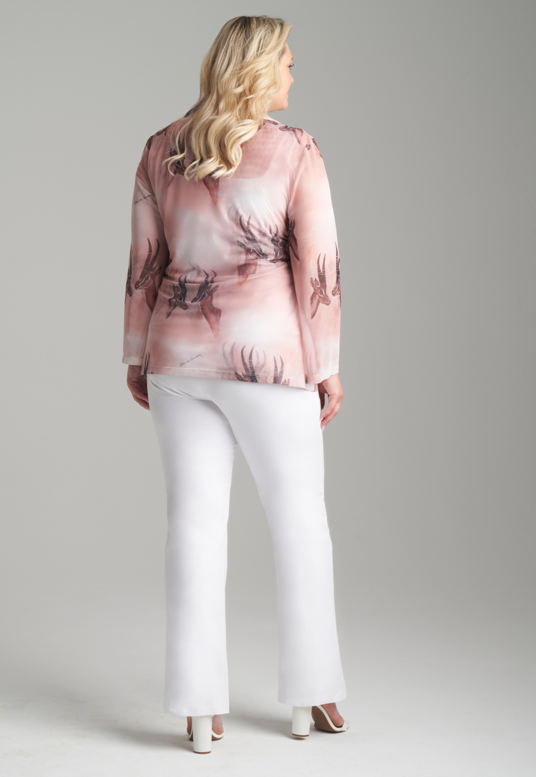 Woman wearing mesh v-neck sweater with organza collar in brown deer print paired with white stretch knit pants by Ala von Auersperg for fall 2023