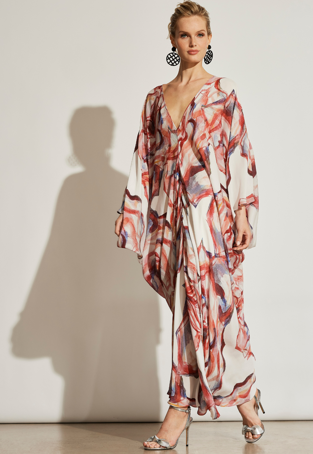 Woman wearing long silk kaftan in a red rose print