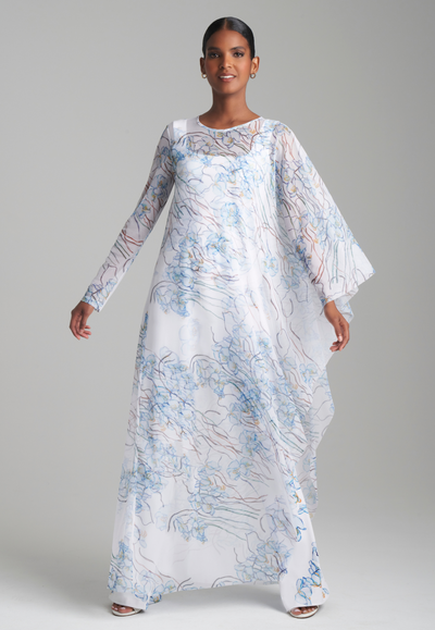 Woman wearing mesh one armed kaftan in a blue orchid print layered over a white and blue floral printed stretch knit tank top and pants by Ala von Auersperg for spring 2024
