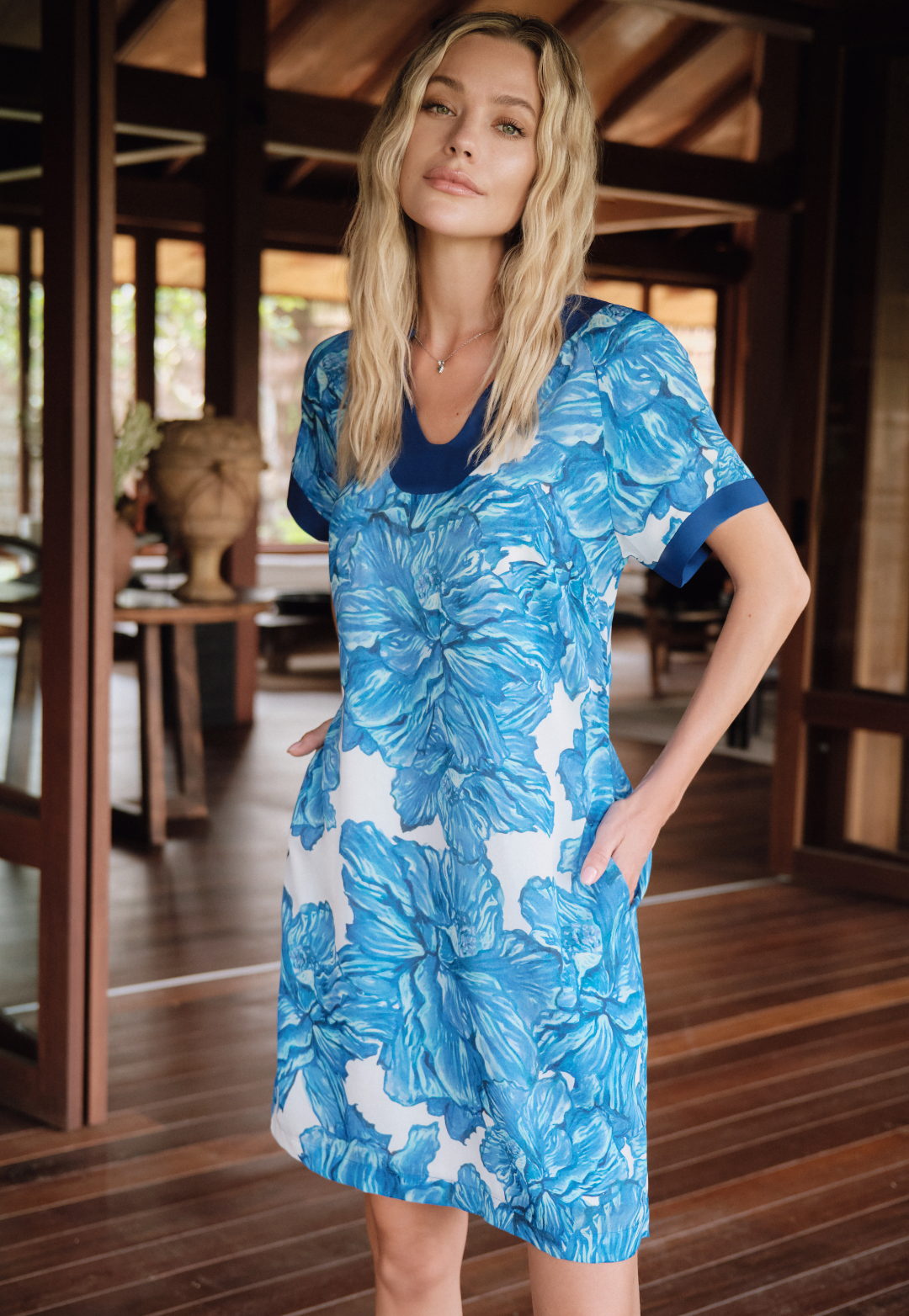 Woman wearing a blue floral dress in a wooden interior setting