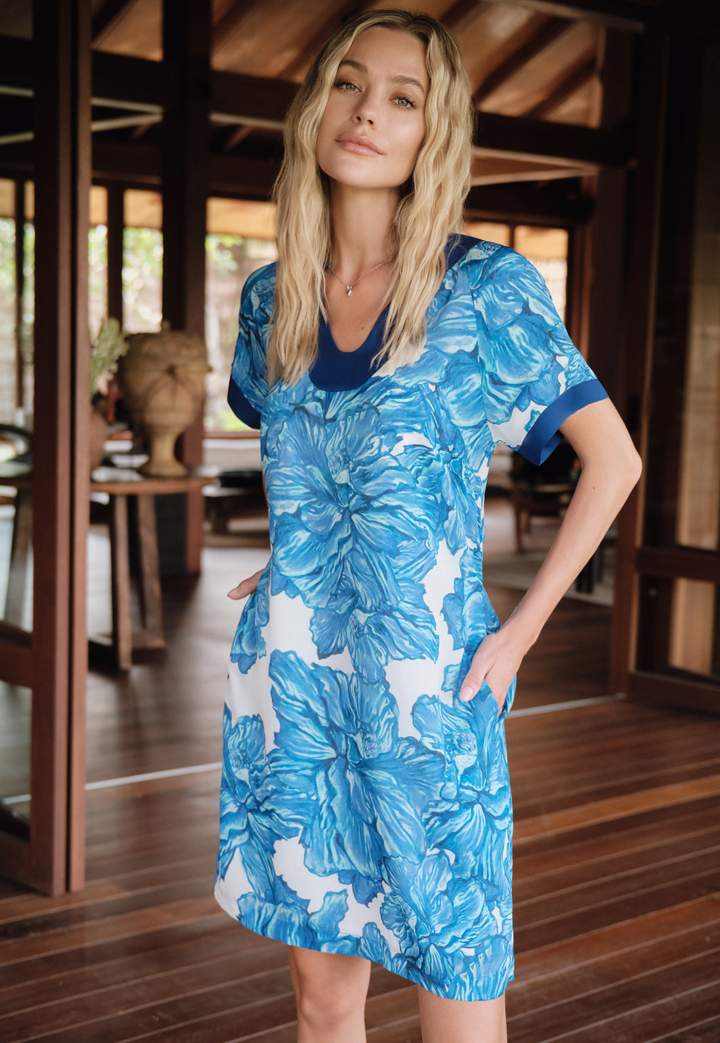 Woman wearing a blue floral dress in a wooden interior setting