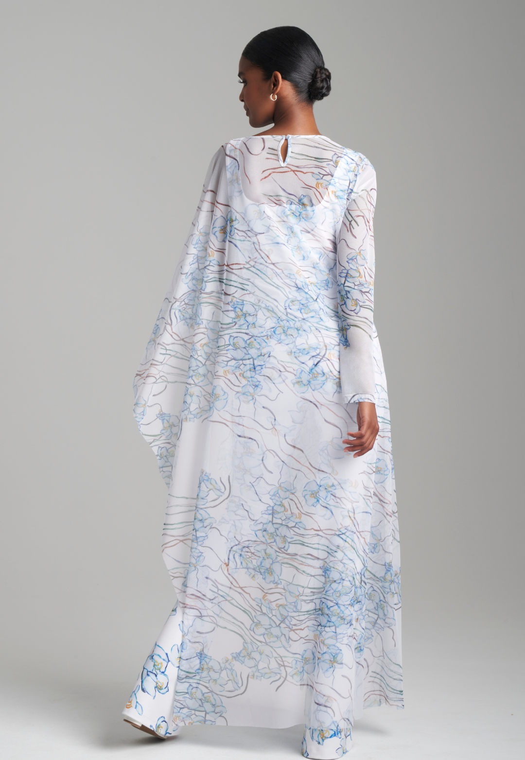 Woman wearing white and blue mesh one armed kaftan poncho over matching tank top and pants by Ala von Auersperg for spring 2024