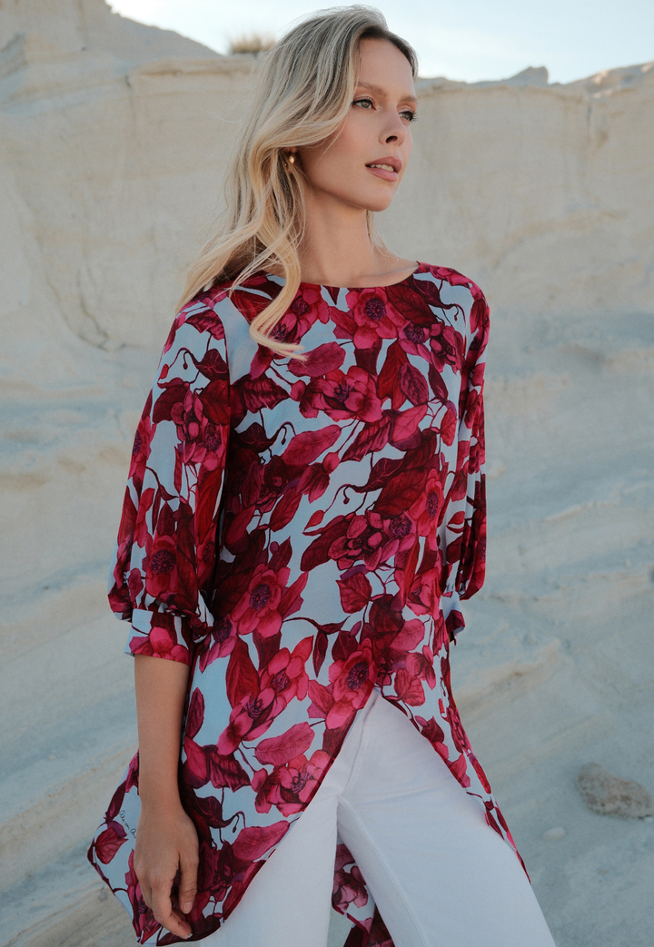 Woman wearing a red floral dress against a beige wall.