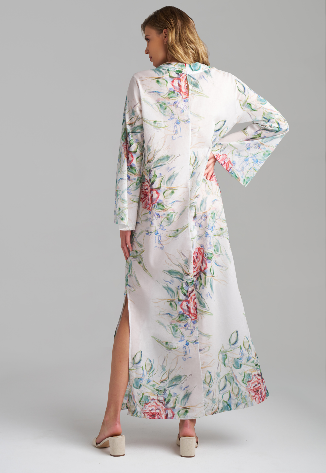 Woman wearing rose printed cotton bell sleeved long kaftan with figure 8 collar detailing by Ala von Auersperg for summer 2023