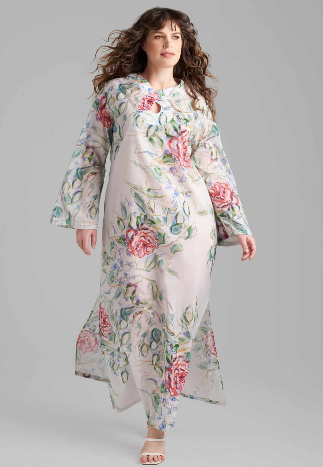 Woman wearing rose printed cotton bell sleeved long kaftan with figure 8 collar detailing by Ala von Auersperg for summer 2023
