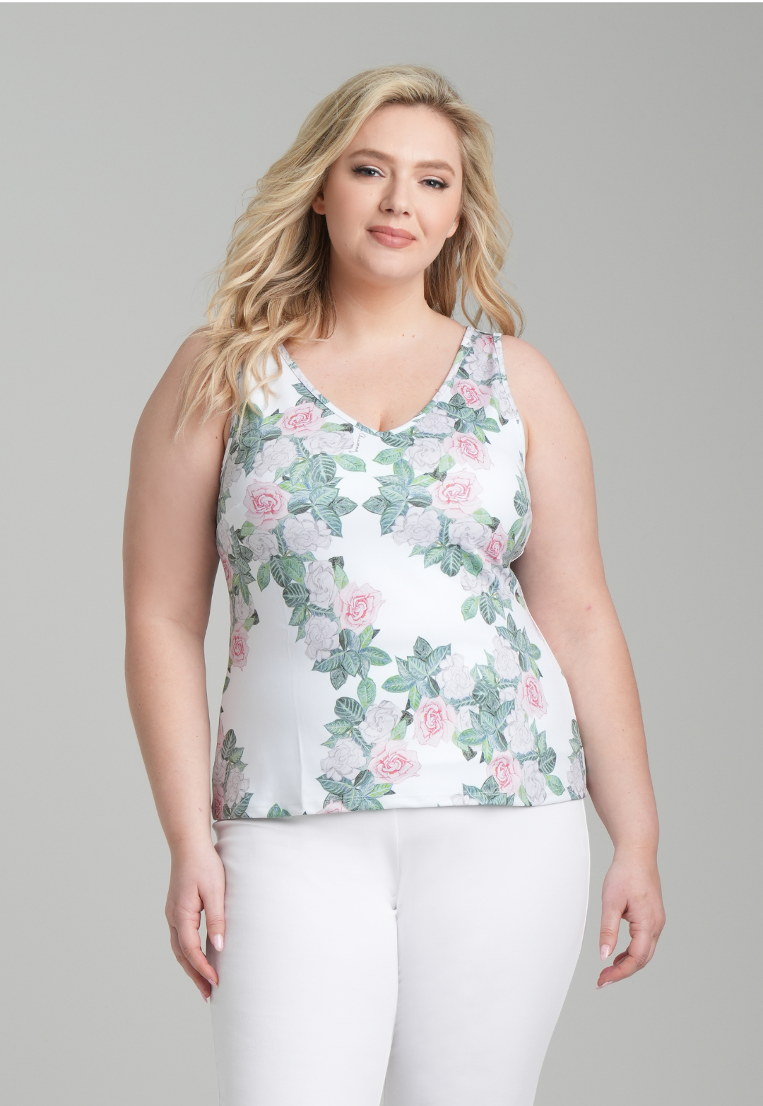 Woman wearing floral printed stretch knit tank top and white pants by designer Ala
 von Auersperg for womens luxury travel clothing
