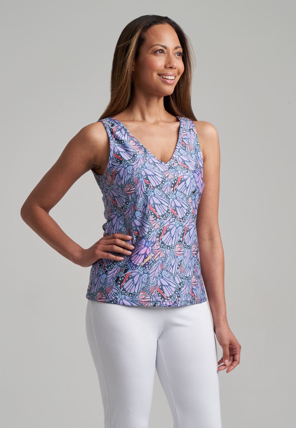 Woman wearing purple butterfly printed v neck stretch tank with white pants by designer Ala von Auersperg for womens luxury travel clothing