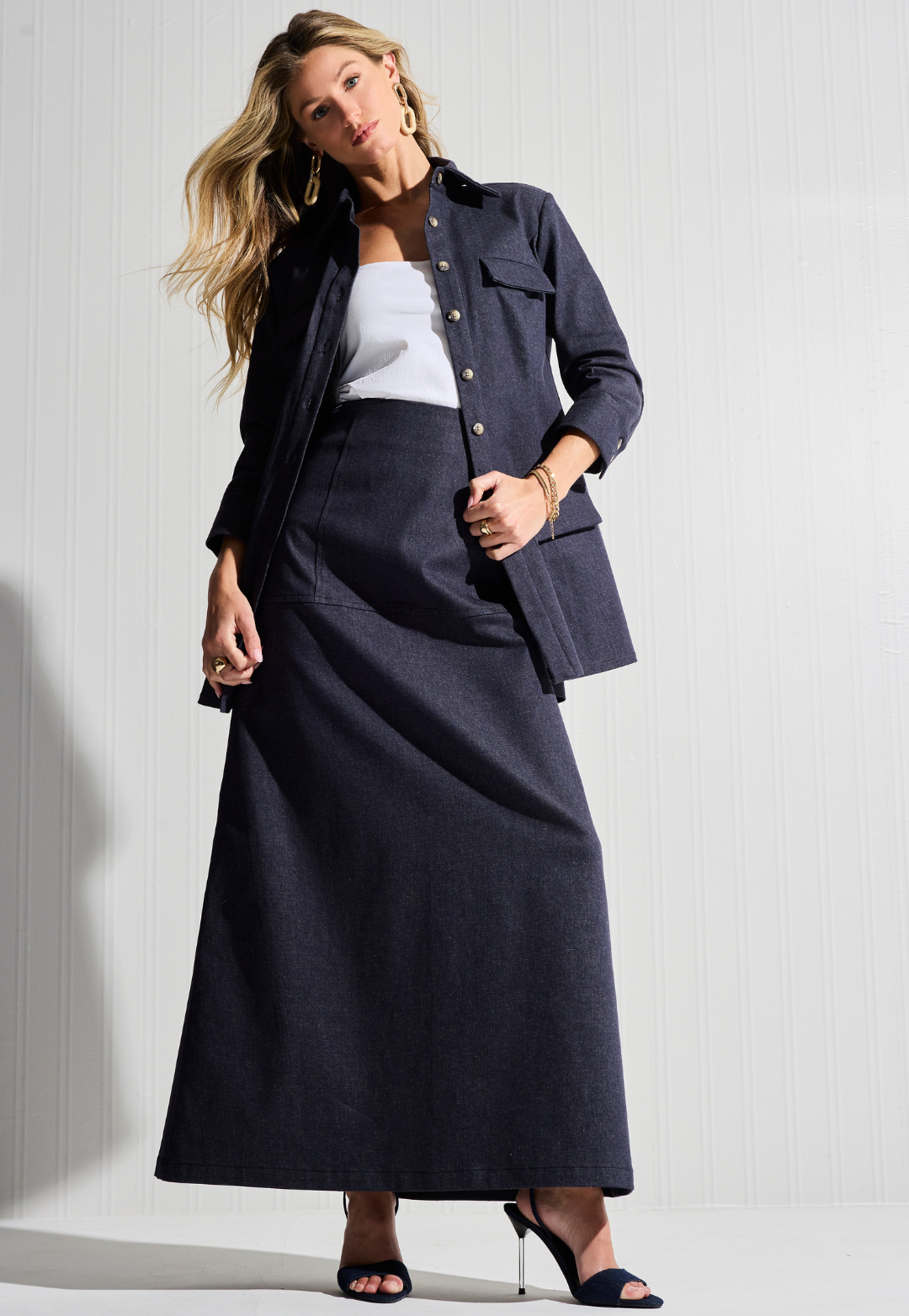 Woman wearing white cotton tank top with denim long skirt and denim jacket open by designer Ala von Auersperg for womens luxury travel clothing