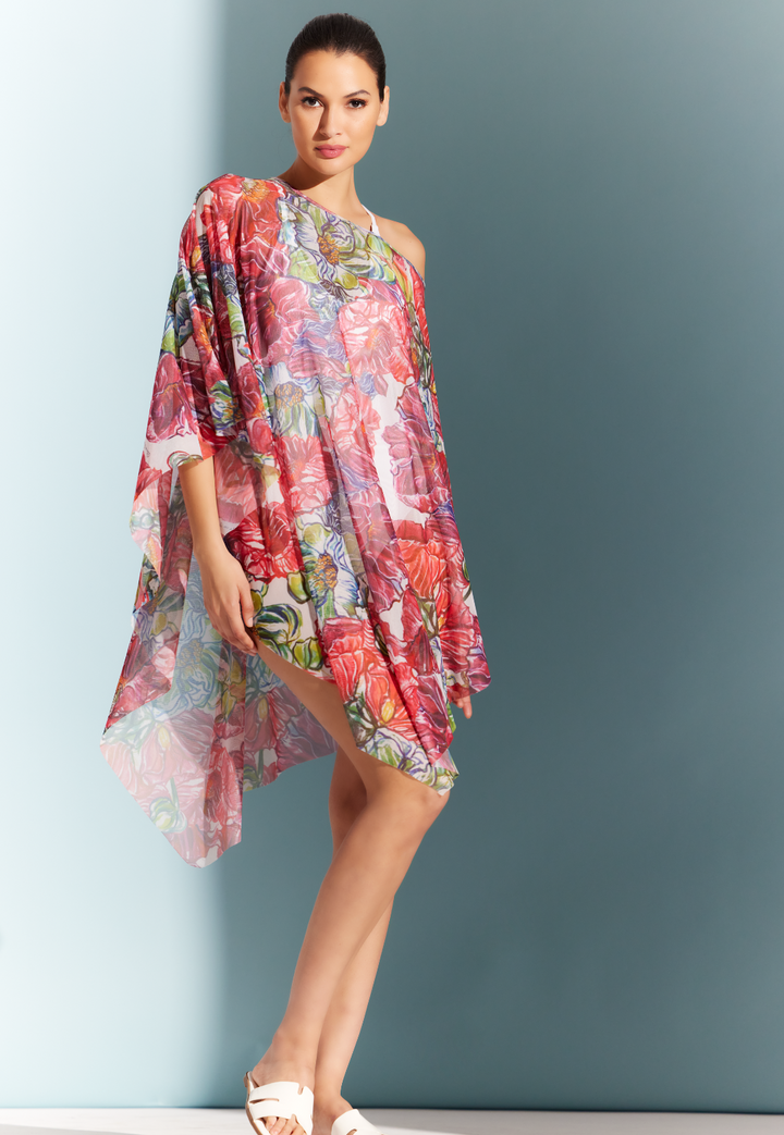 Woman wearing mesh cover up poncho over a swimsuit in a red floral print by designer Ala von Auersperg for womens luxury travel clothing
