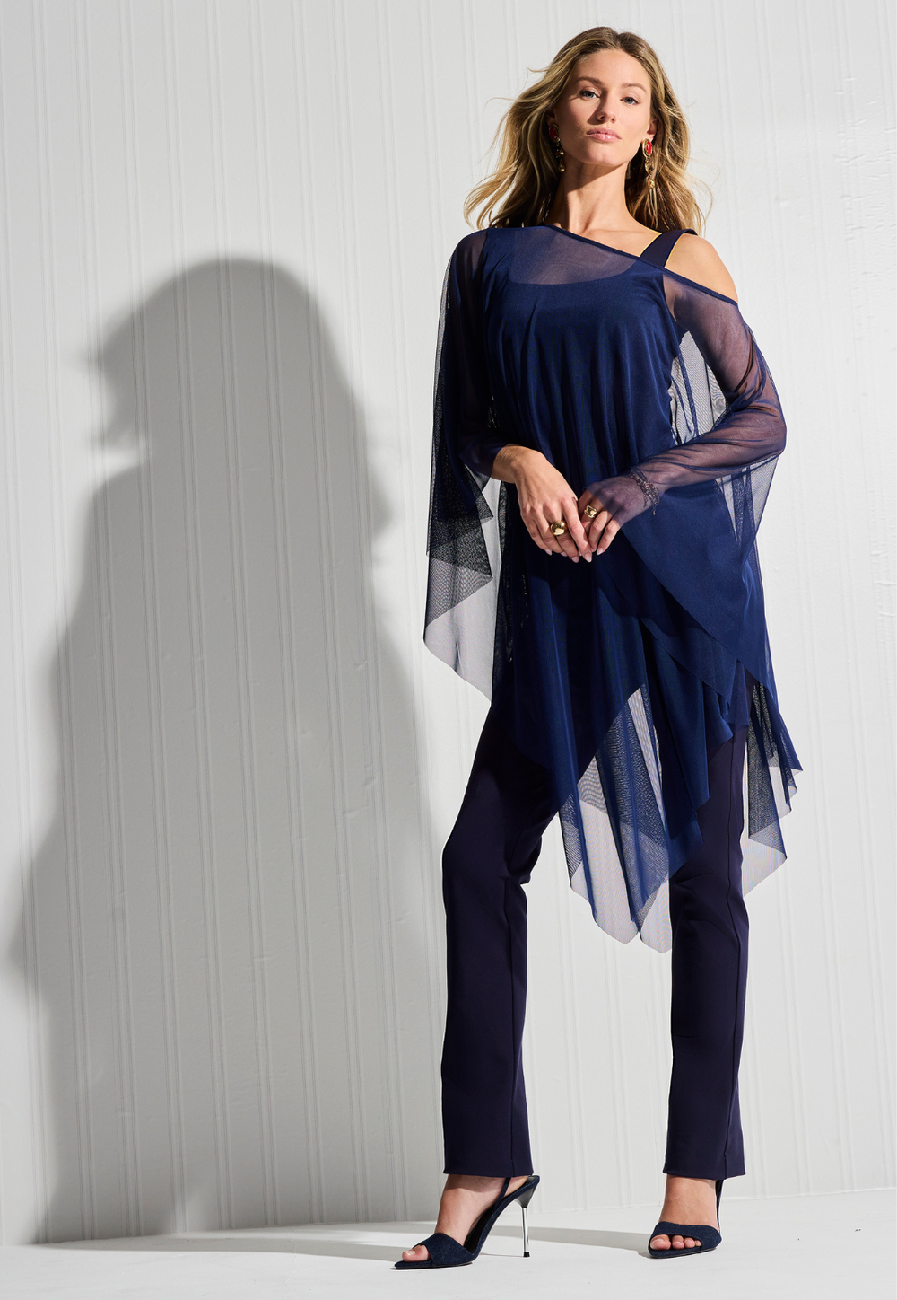 Woman wearing navy mesh poncho over navy tank top and pants by designer Ala von Auersperg for womens luxury travel clothing