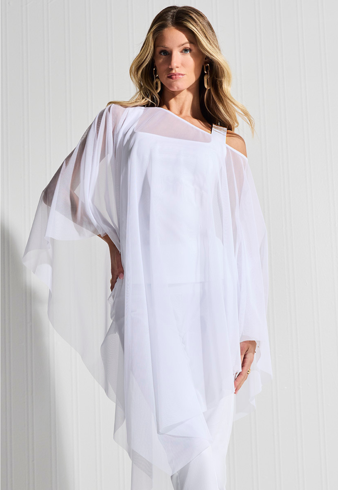 Woman wearing white mesh poncho over matching tank top and pants by designer Ala von Auersperg for womens luxury travel clothing