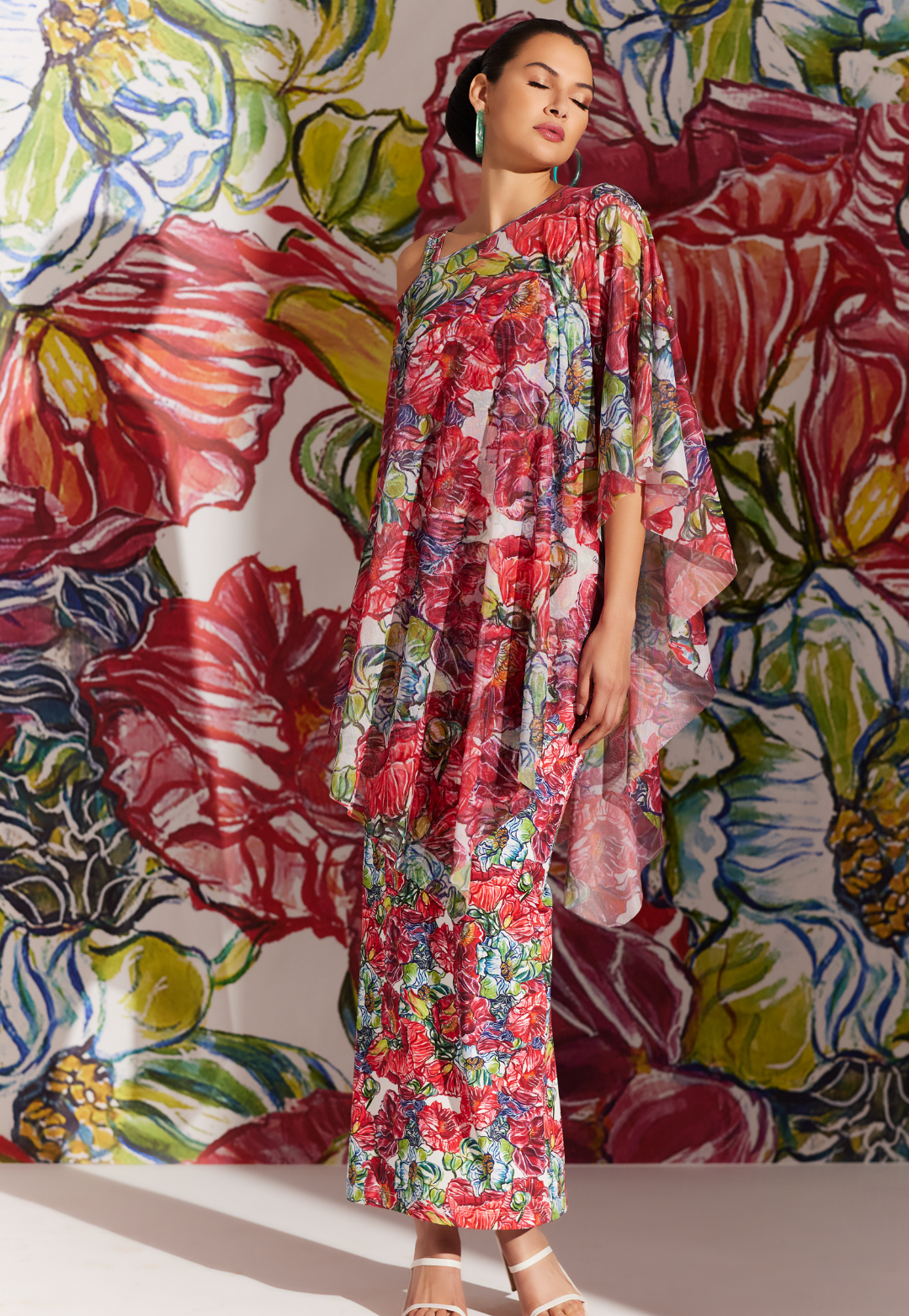 Woman wearing sheer mesh poncho over matching long stretch knit dress in a red floral print by designer Ala von Auersperg for womens luxury travel clothing