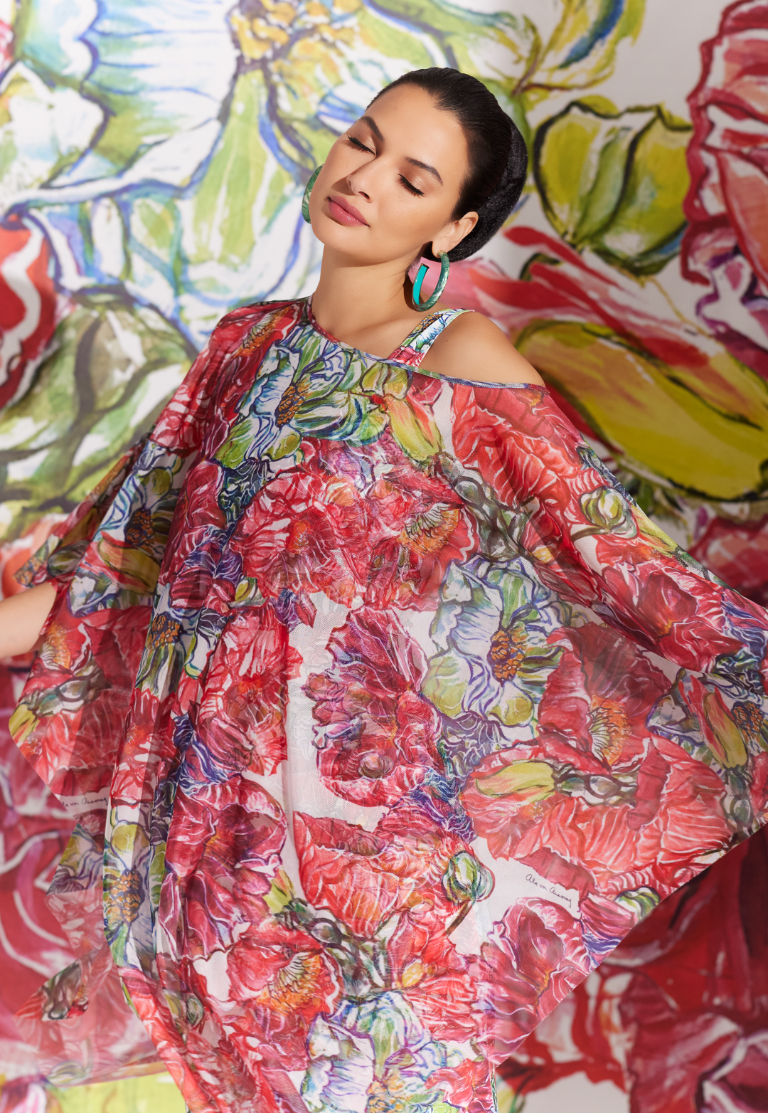 Woman wearing sheer poncho over matching long stretch knit dress in a red floral print by designer Ala von Auersperg for womens luxury travel clothing