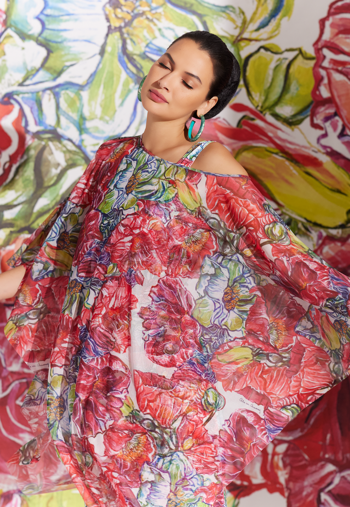 Woman wearing sheer poncho over matching long stretch knit dress in a red floral print by designer Ala von Auersperg for womens luxury travel clothing
