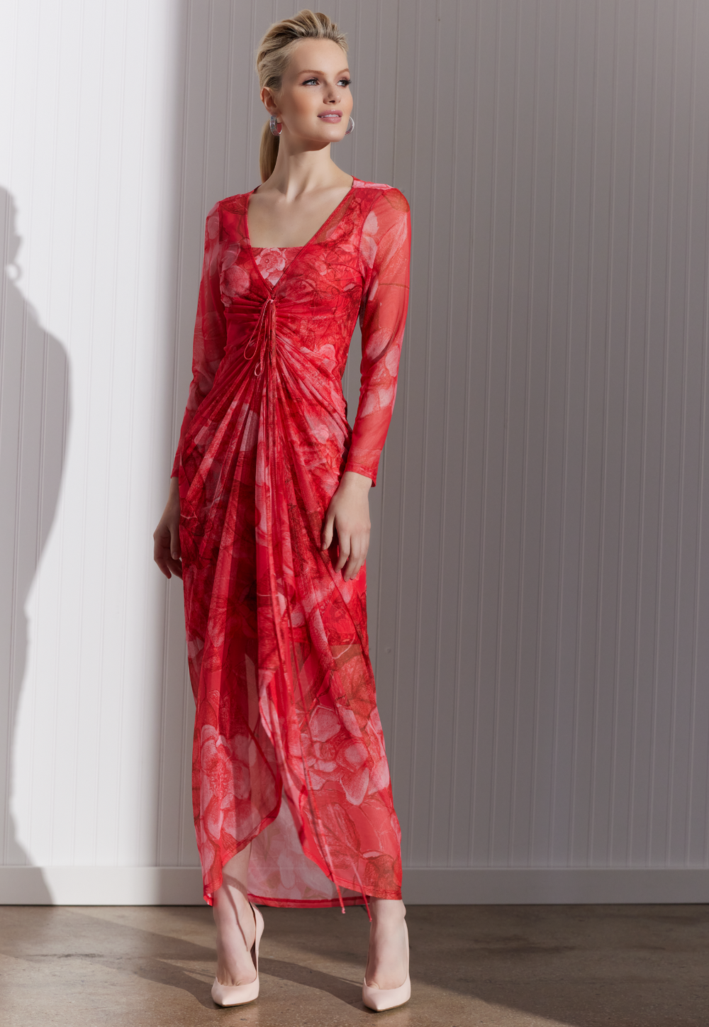 Woman wearing sheer drawstring dress over matching mini dress in a red floral print by designer Ala von Auersperg for women's luxury travel fashion