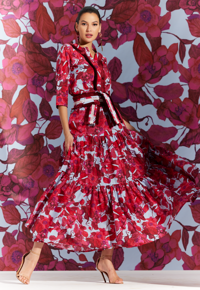 Woman wearing tiered cotton maxi skirt with a tunic and sash in a matching red floral print by designer Ala von Auersperg for women's luxury travel clothing