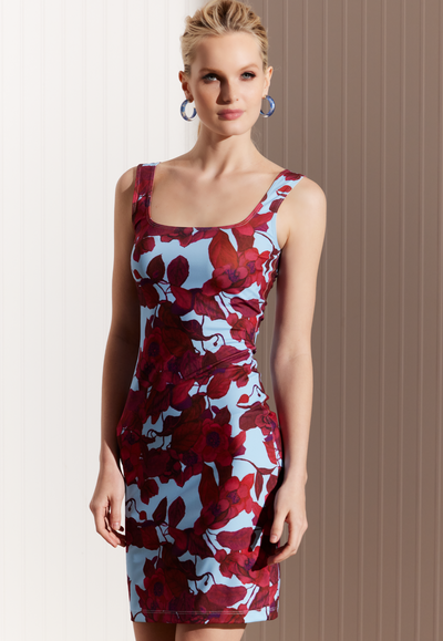 Woman wearing stretch knit short mini dress in a red floral print and a blue background by designer Ala von Auersperg for womens luxury travel clothing