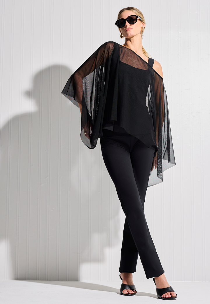 Woman wearing short mesh sheer poncho over tank top and pants all in black with sunglasses by designer Ala von Auersperg for womens luxury travel clothing