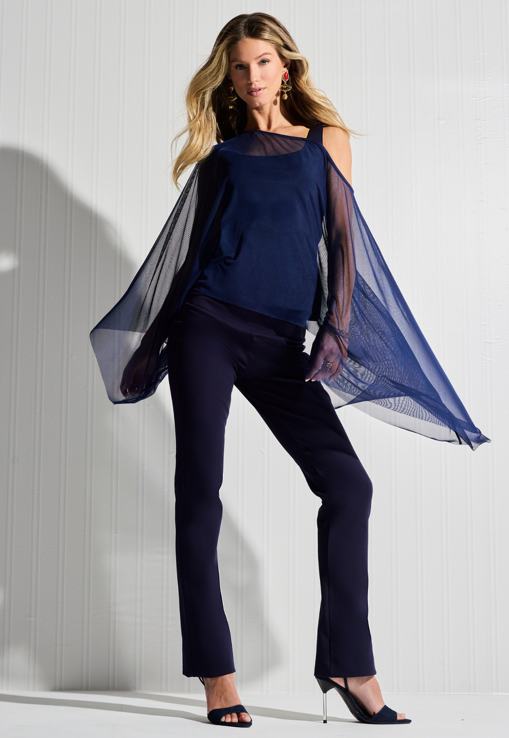 Woman wearing navy mesh sheer poncho over navy tank top and pants by designer Ala von Auersperg for womens luxury travel clothing
