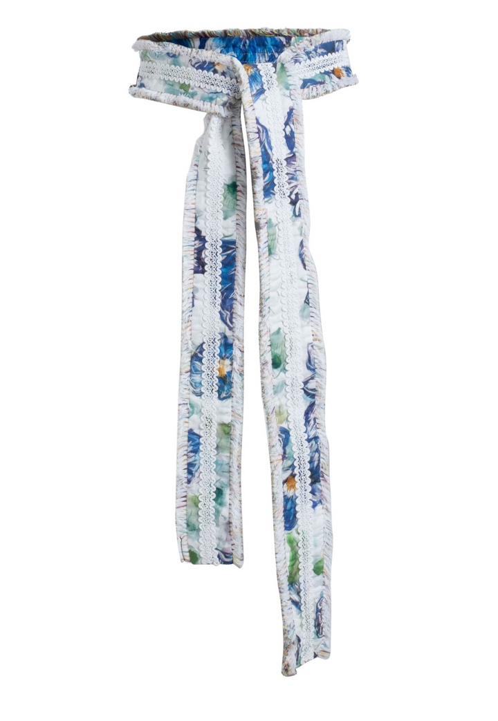 Flat image of a belt in a blue floral print with italian fringe trim by designer Ala von Auersperg for womens luxury travel clothing