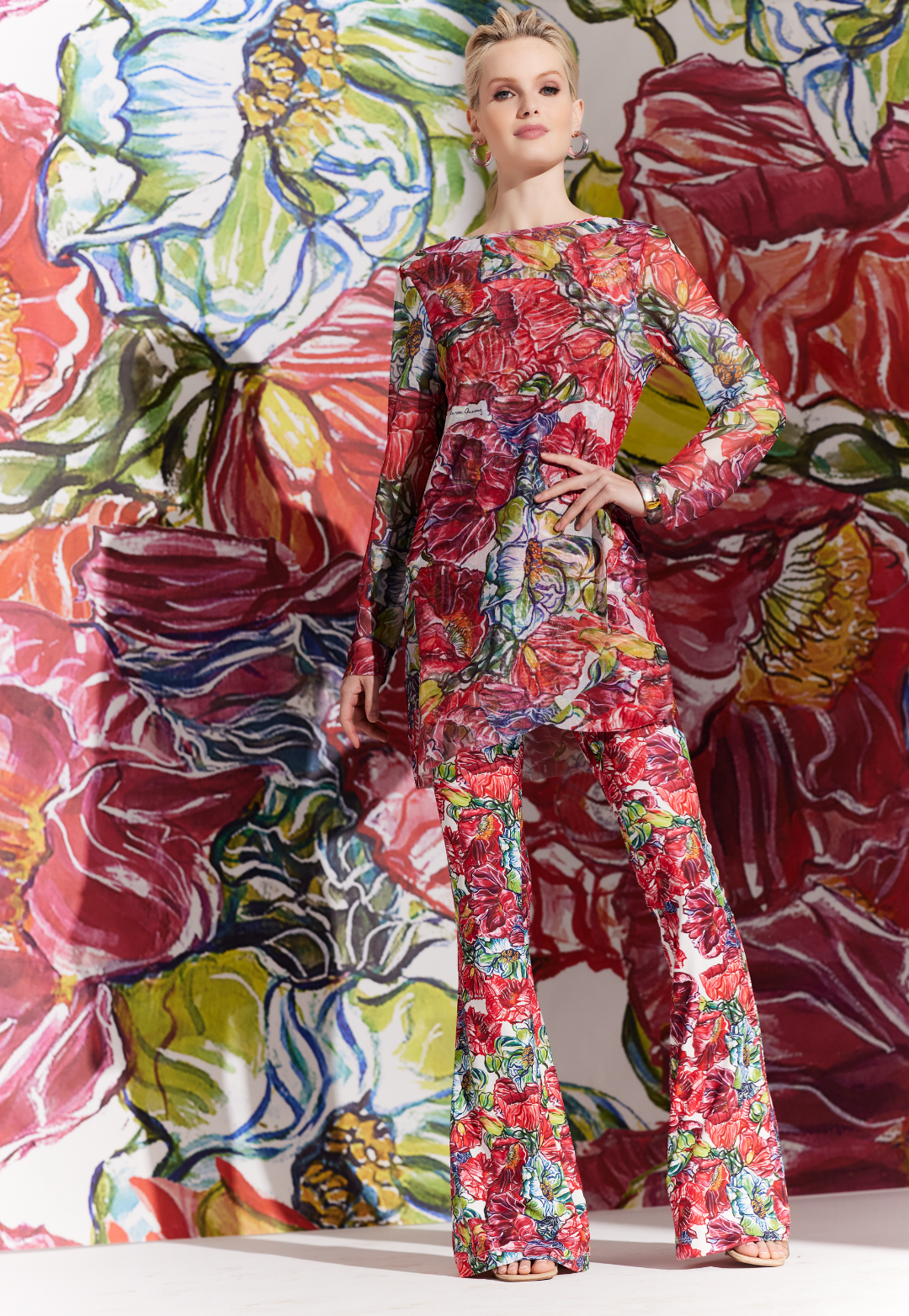 Woman wearing sheer mesh top over a matching tank top and pants in a red floral print by designer Ala von Auerperg for womens luxury travel clothing